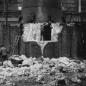 Demolition of brickwork at base of metal chimney with 6 workers